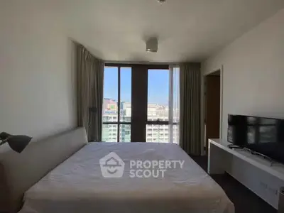 Spacious bedroom with large window offering city views, featuring a comfortable bed and modern decor.