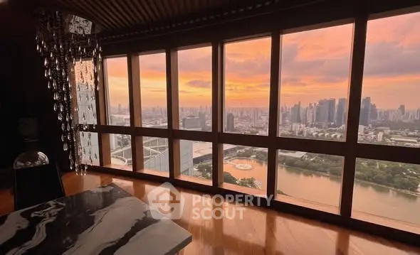 Stunning high-rise view with floor-to-ceiling windows overlooking city skyline at sunset.
