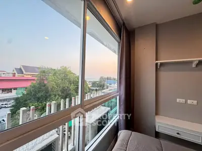 Cozy bedroom with large window offering a serene view of the cityscape and greenery.