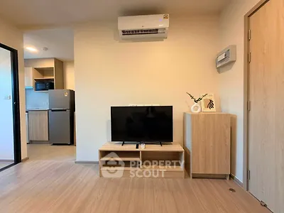Modern living room with wooden flooring, TV unit, and air conditioning, adjacent to a sleek kitchen.