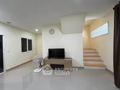 Modern living room with TV, fan, and staircase in minimalist design