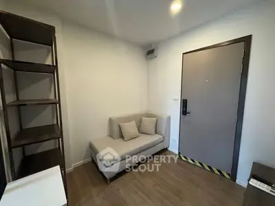 Cozy small living room with modern sofa and open shelving unit.