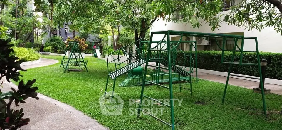 Charming garden with playground equipment in a residential complex, perfect for family living.