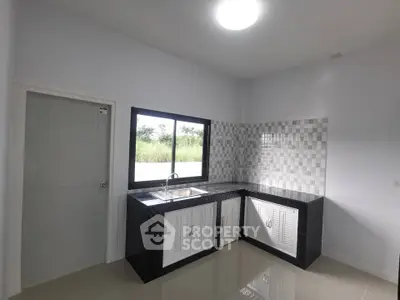 Modern kitchen with sleek black and white design, featuring a large window and tiled backsplash.
