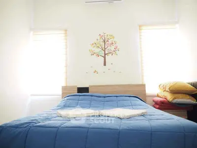 Cozy bedroom with bright windows and charming tree wall decal.