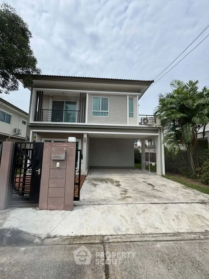 Modern two-story house with driveway and balcony in a suburban neighborhood.