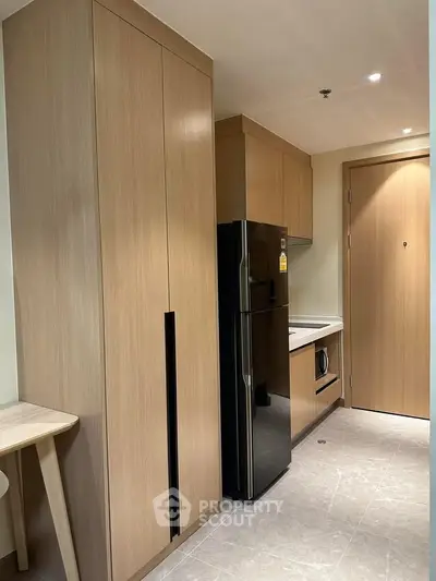 Modern kitchen with sleek wooden cabinetry and stainless steel appliances in a compact layout.