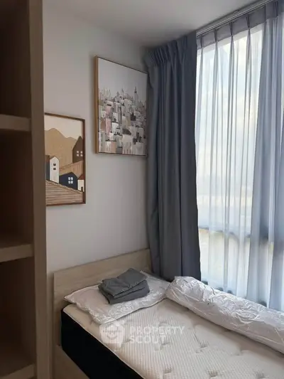 Cozy bedroom with natural light, modern decor, and comfortable bedding in a stylish apartment.