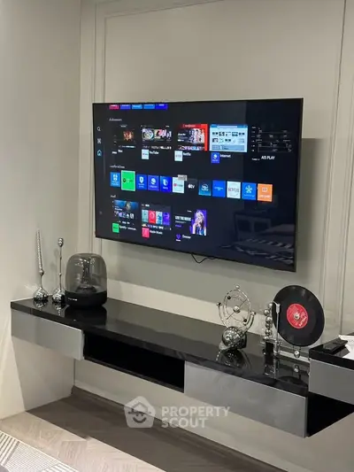 Modern living room with wall-mounted TV and sleek black console.