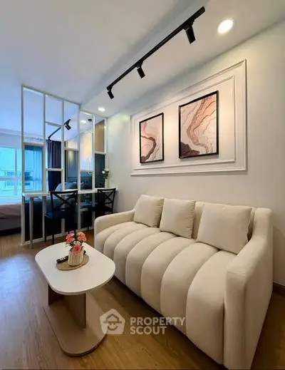 Modern living room with elegant decor and open layout, featuring a cozy sofa and stylish artwork.