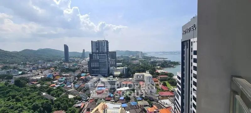 Stunning cityscape view from high-rise building balcony with ocean backdrop.