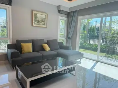 Spacious living room with modern sofa and garden view through large windows.