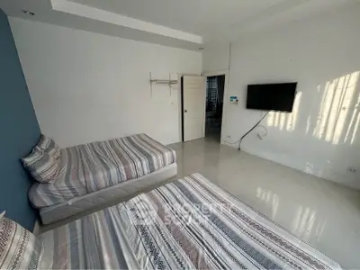 Spacious bedroom with modern decor and twin beds, featuring a wall-mounted TV and ample natural light.