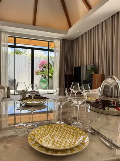Luxurious living room with elegant dining setup and garden view, featuring high ceilings and modern decor.