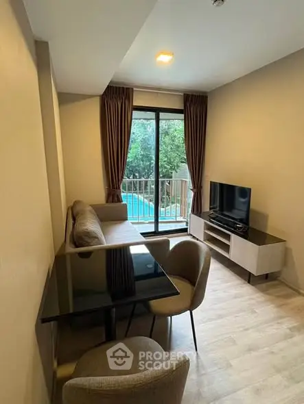 Modern living room with pool view, featuring sleek furniture and large window for natural light.