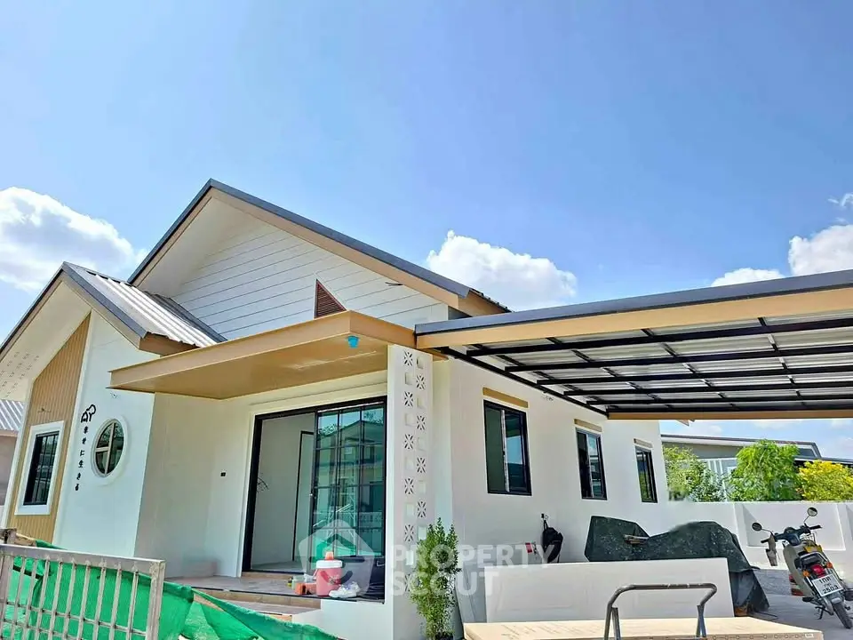 Modern single-story house with sleek design and spacious carport under clear blue sky.