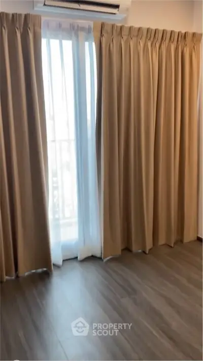Spacious room with large window and elegant curtains, perfect for natural light and modern living.