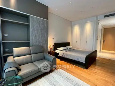 Modern bedroom with sleek design, featuring a cozy bed, stylish sofa, and built-in storage in a contemporary apartment.