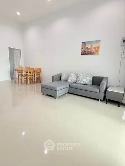 Spacious living room with modern gray sofa and dining area, perfect for family gatherings.