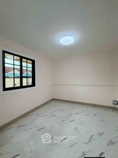 Spacious unfurnished room with modern flooring and large window, ideal for customization.