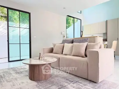 Modern living room with plush sofa and stylish coffee table, featuring large windows and natural light.