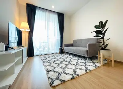 Modern living room with stylish decor, featuring a cozy sofa, elegant rug, and large window with natural light.