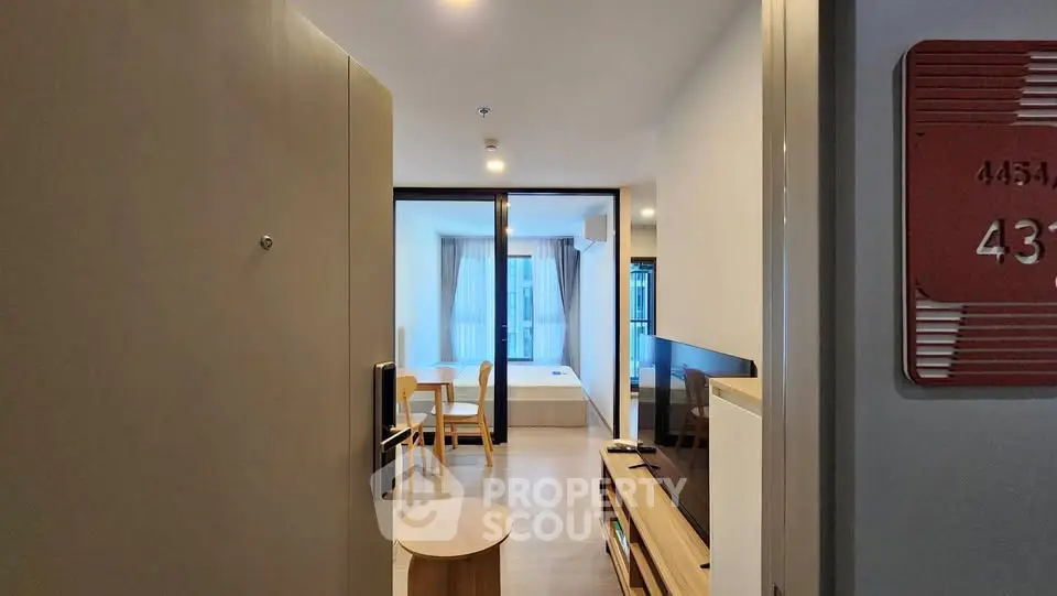 Modern apartment entrance leading to a cozy living area with dining set and TV unit.