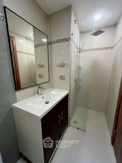 Modern bathroom with sleek shower and stylish vanity in contemporary apartment.