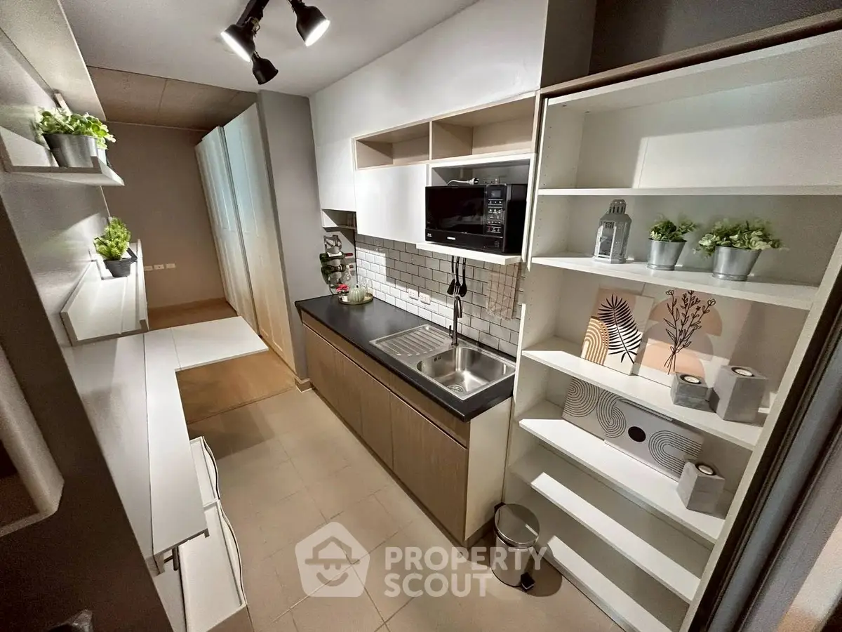 Modern kitchen with sleek cabinetry and built-in microwave, featuring open shelving and stylish decor.