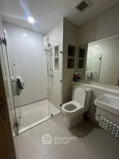 Modern bathroom with glass shower and sleek fixtures in contemporary apartment.