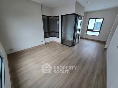 Spacious modern living room with large windows and wood flooring in a contemporary apartment.