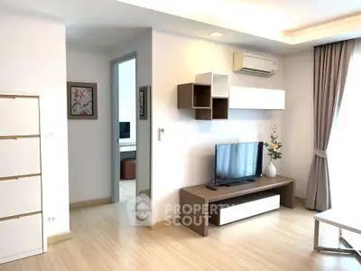 Modern living room with sleek furniture and natural light, featuring a wall-mounted TV and air conditioning.