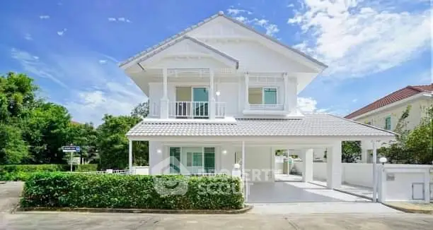 Stunning white two-story house with lush greenery and clear blue sky