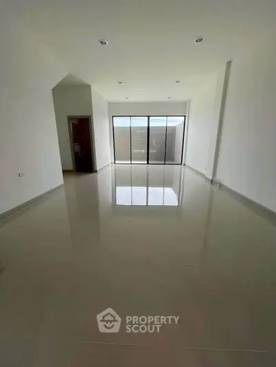 Spacious empty living room with large windows and glossy tiled floor