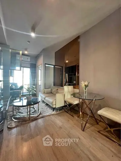 Modern living room with elegant decor and natural light, featuring a cozy seating area and stylish glass table.