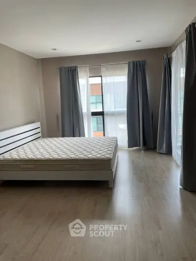 Spacious bedroom with large windows and natural light, featuring modern minimalist design.