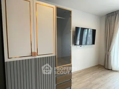 Modern bedroom with stylish wardrobe and wall-mounted TV in a bright apartment.