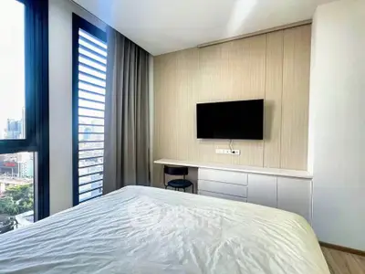 Modern bedroom with city view, featuring a sleek TV setup and stylish decor.