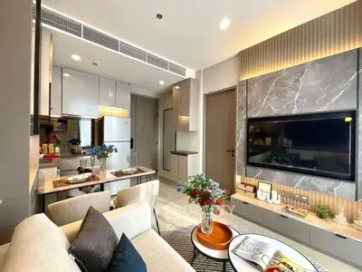 Modern living room with open kitchen, stylish decor, and cozy seating area.