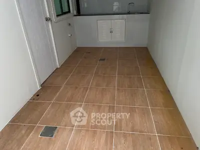 Spacious tiled room with sink and storage, ideal for utility or laundry use.