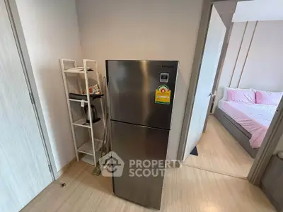 Modern apartment interior with stainless steel fridge and cozy bedroom view.