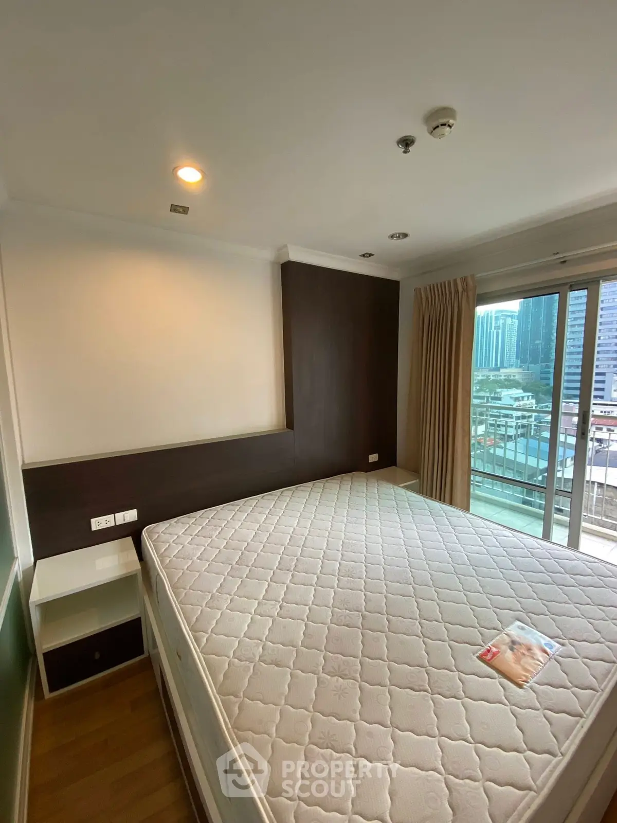 Spacious bedroom with large window and city view, featuring a comfortable bed and modern decor.