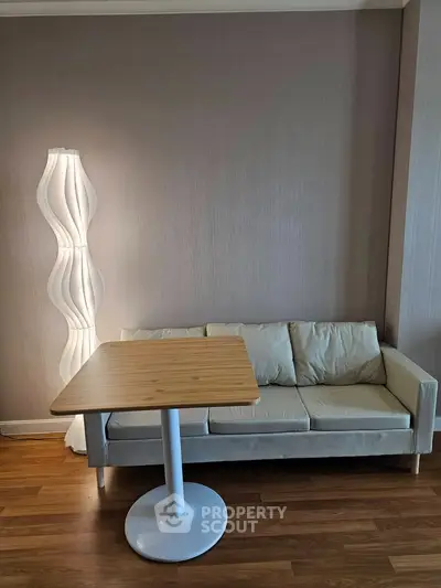 Modern living room with stylish sofa, unique floor lamp, and wooden table on elegant hardwood flooring.