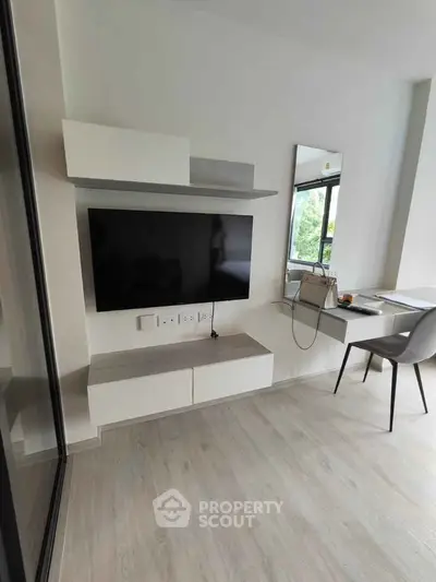 Modern living room with sleek TV setup and stylish workspace, perfect for urban living.
