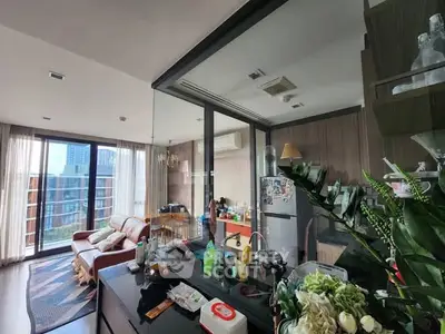 Modern living room with open kitchen and city view, featuring stylish decor and natural light.