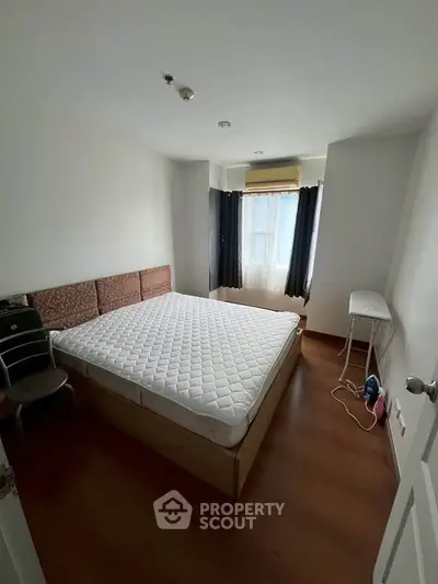 Cozy bedroom with natural light and minimalist decor, featuring a comfortable bed and wooden flooring.
