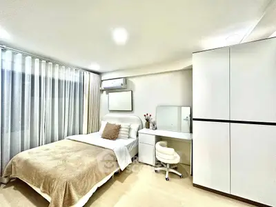 Modern bedroom with cozy bed, sleek wardrobe, and stylish vanity in bright apartment.