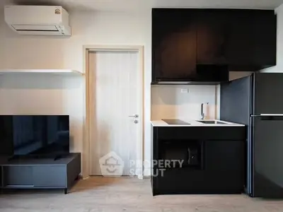 Modern kitchen with sleek black cabinets and integrated appliances in a stylish apartment.