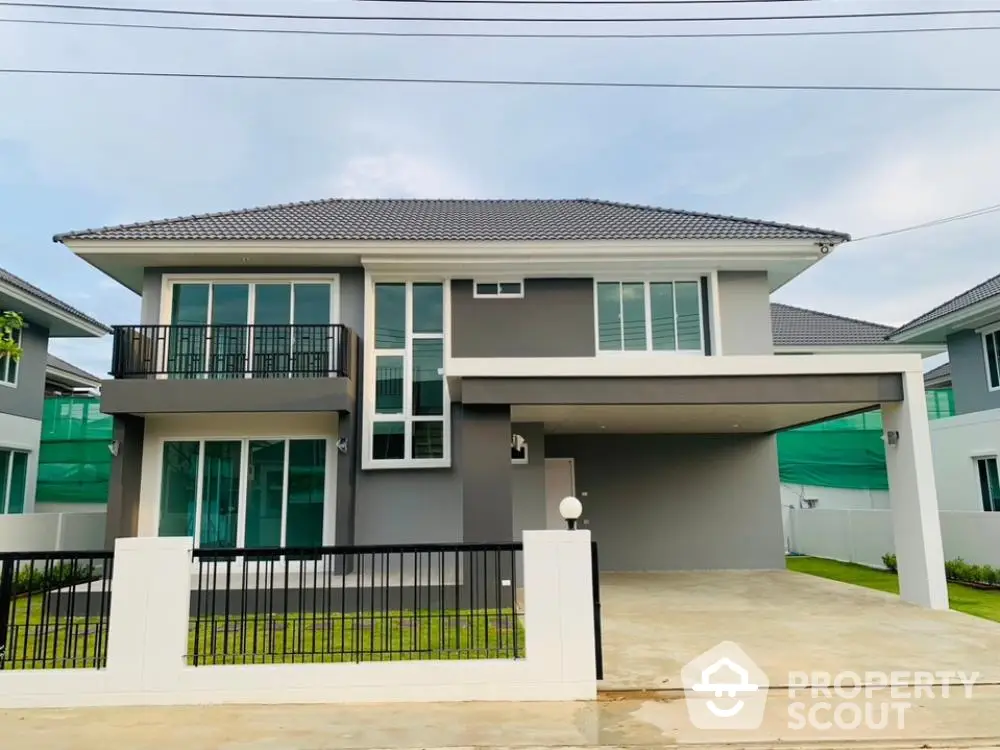 Modern two-story house with sleek design and spacious driveway in suburban neighborhood.