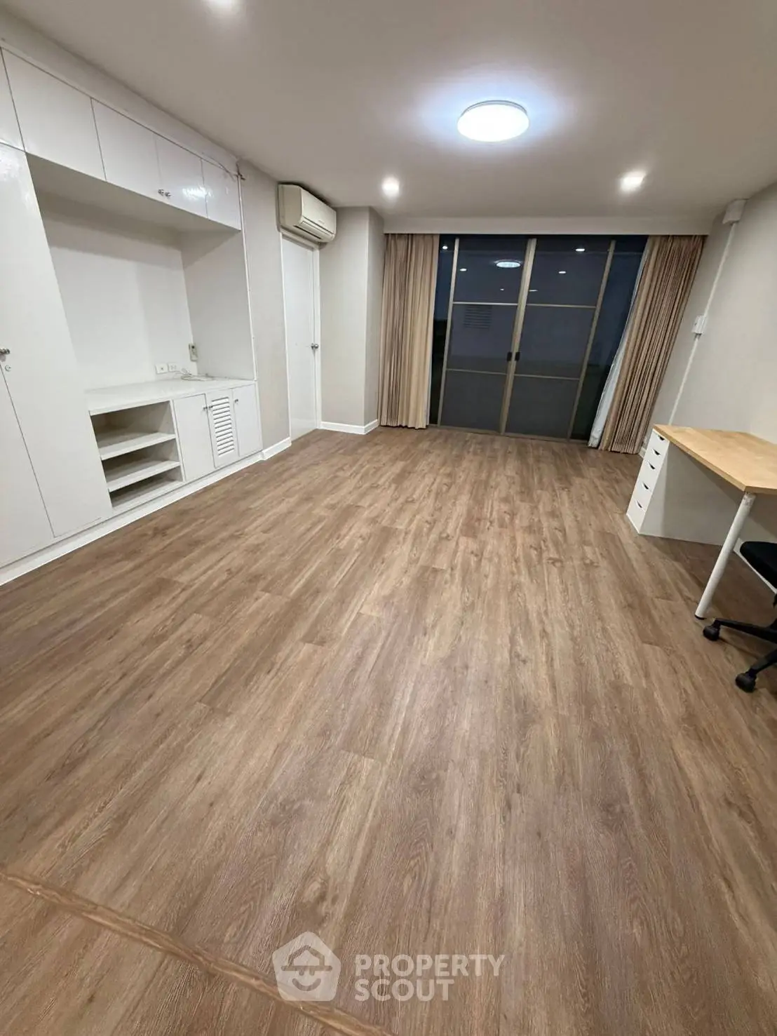 Spacious living room with wooden flooring and modern built-in storage, perfect for cozy gatherings.